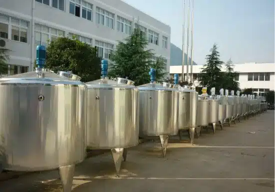 A row of stainless steel tanks in front of a building