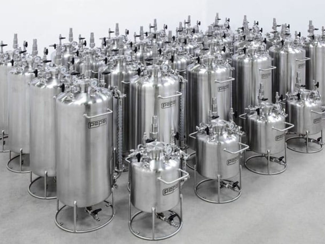 a group of stainless steel tanks lined up in a room.