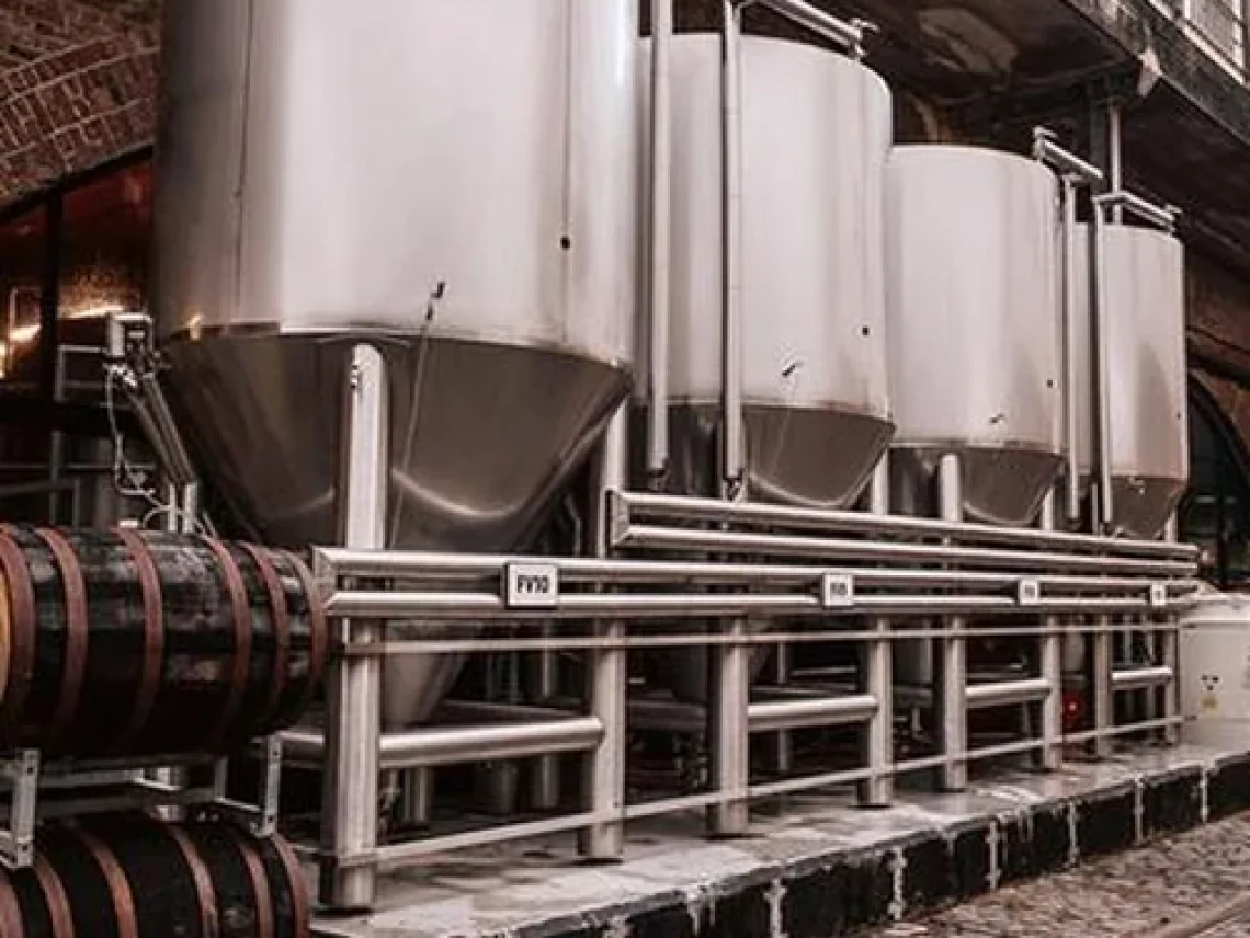 a row of metal tanks sitting next to a bridge