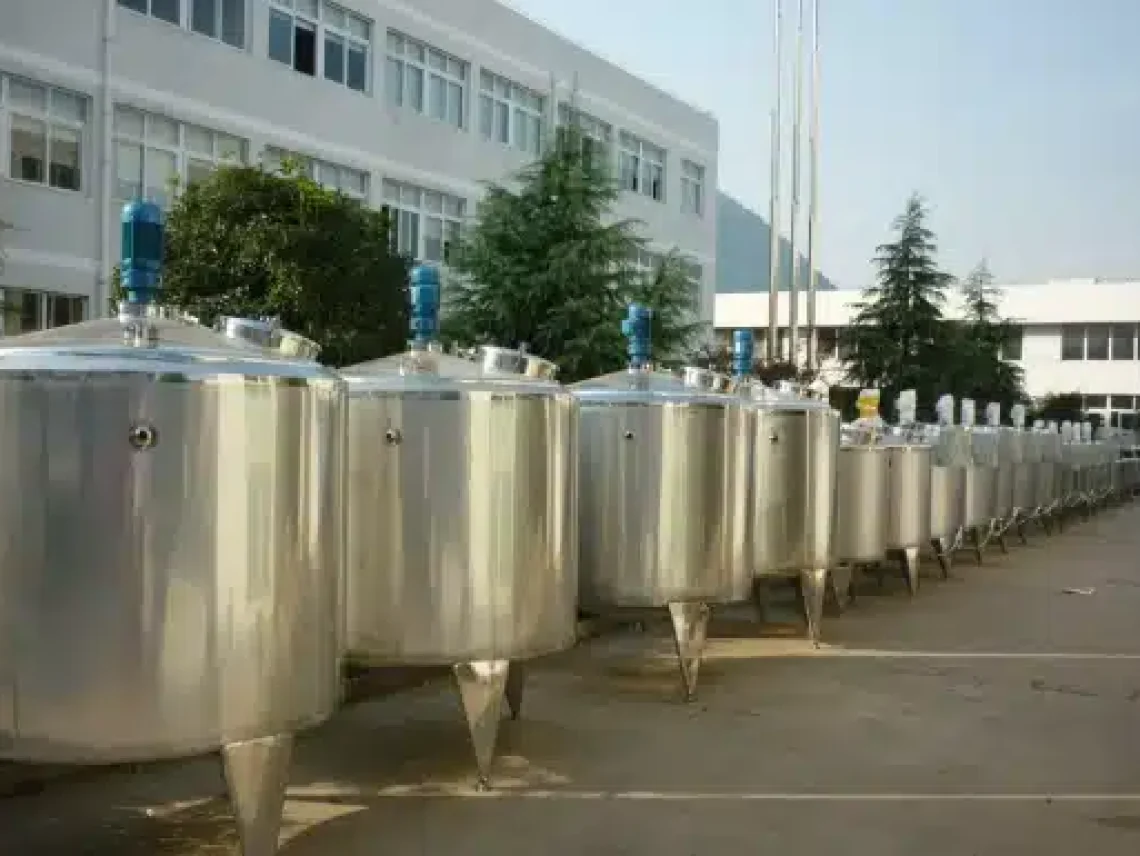 A row of stainless steel tanks in front of a building