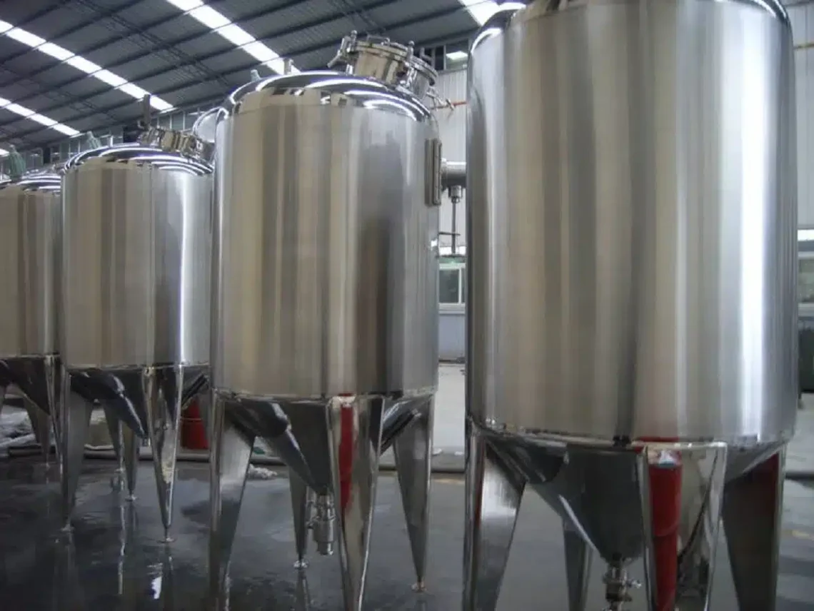 A row of stainless steel tanks sitting inside of a building.