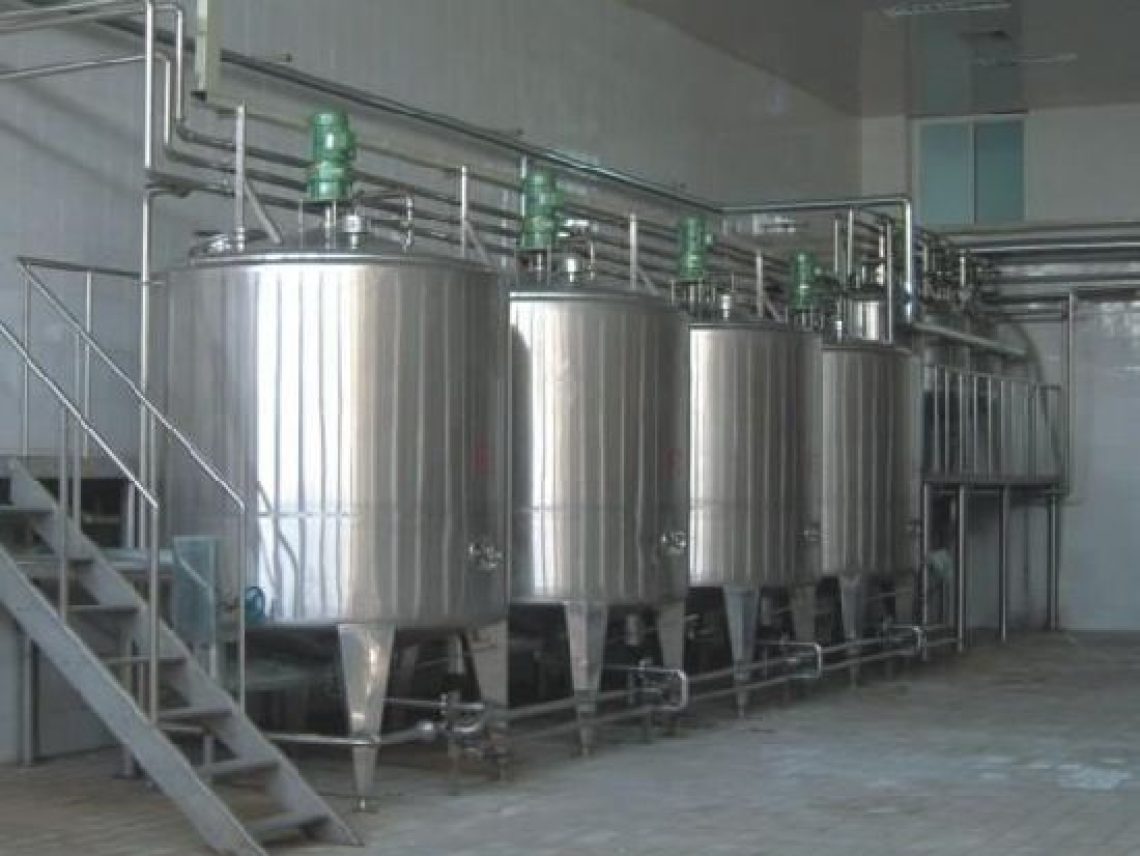 a row of stainless steel tanks sitting inside of a building