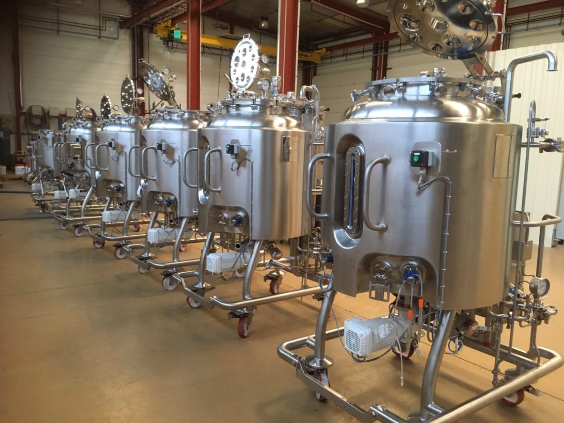 a row of stainless steel tanks sitting inside of a building